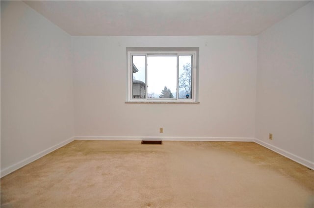 empty room featuring light carpet, baseboards, and visible vents