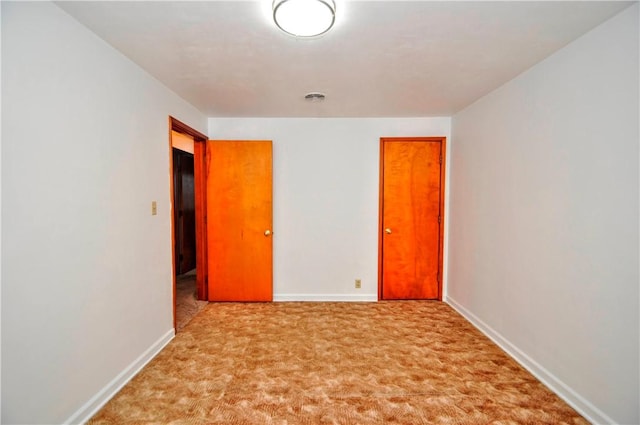 spare room featuring baseboards, visible vents, and carpet flooring