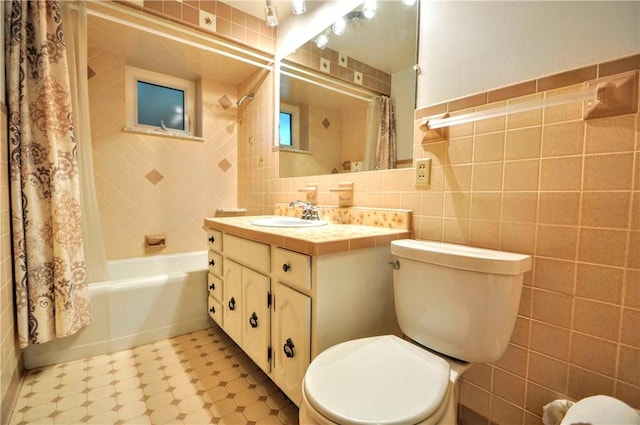 full bath with toilet, tile patterned floors, shower / bath combo with shower curtain, vanity, and tile walls