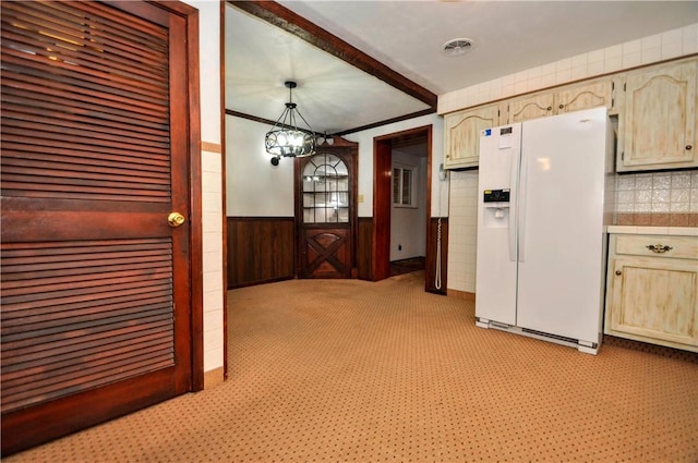 kitchen featuring a wainscoted wall, light countertops, crown molding, white fridge with ice dispenser, and a chandelier