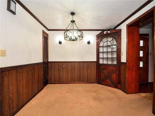 unfurnished dining area with a chandelier, carpet, wainscoting, and wood walls