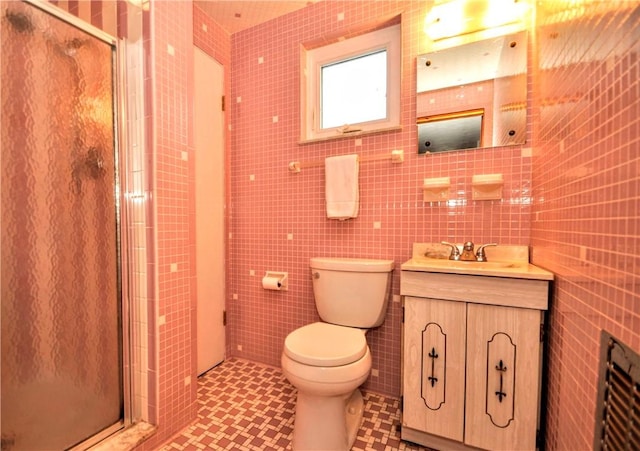 full bath featuring tile patterned flooring, toilet, vanity, tile walls, and a shower stall