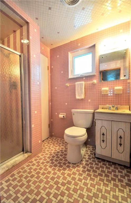 bathroom with vanity, a shower stall, toilet, and tile walls