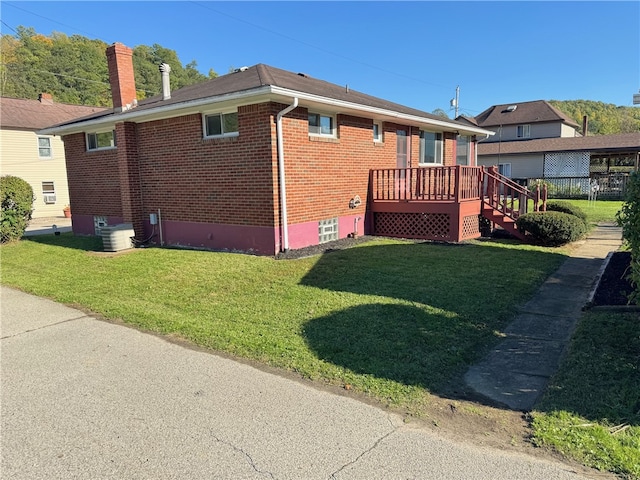 back of property featuring a wooden deck and a lawn