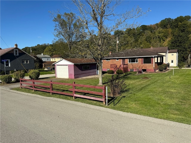 single story home featuring a front yard, a garage, and an outbuilding