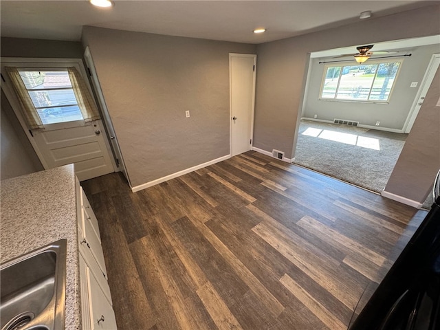 interior space with dark wood-type flooring, white cabinetry, and ceiling fan