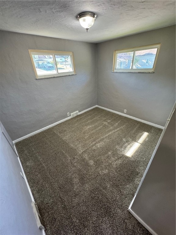 unfurnished room featuring carpet flooring and a textured ceiling