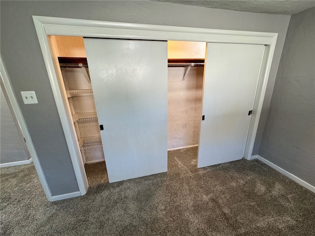 unfurnished bedroom with a closet and dark colored carpet