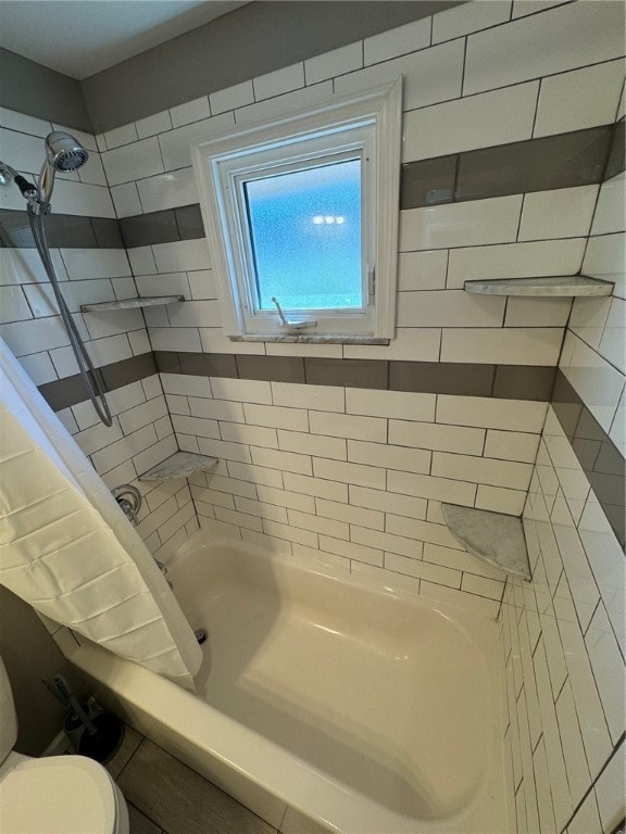 bathroom featuring tiled shower / bath and toilet