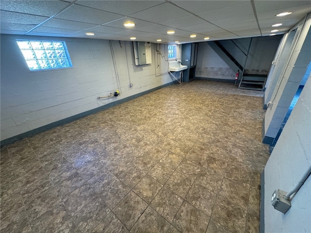 basement with sink, electric panel, and a drop ceiling