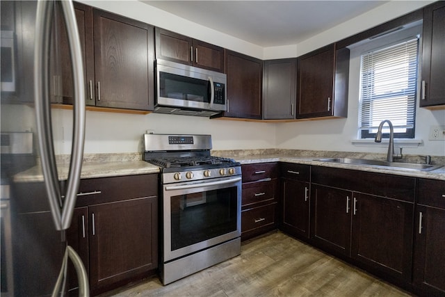 kitchen featuring sink, appliances with stainless steel finishes, dark brown cabinets, and wood-type flooring