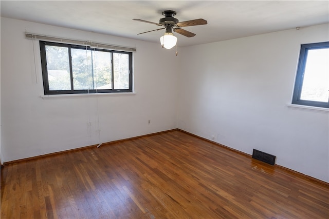 spare room featuring ceiling fan, dark hardwood / wood-style flooring, and plenty of natural light