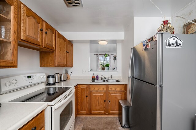 kitchen featuring sink, electric stove, and stainless steel refrigerator