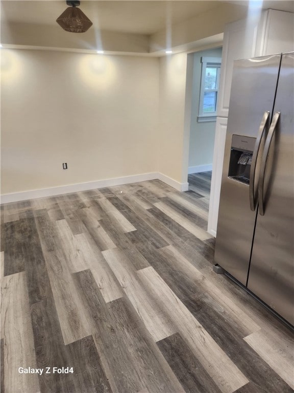 basement with stainless steel fridge with ice dispenser and hardwood / wood-style floors