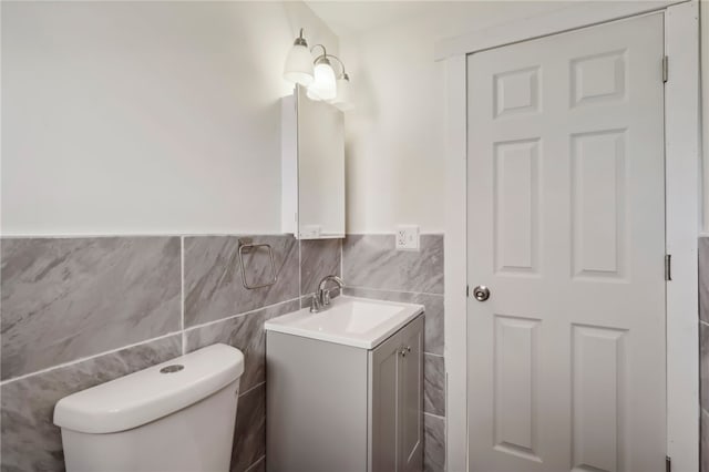 bathroom featuring vanity, toilet, and tile walls