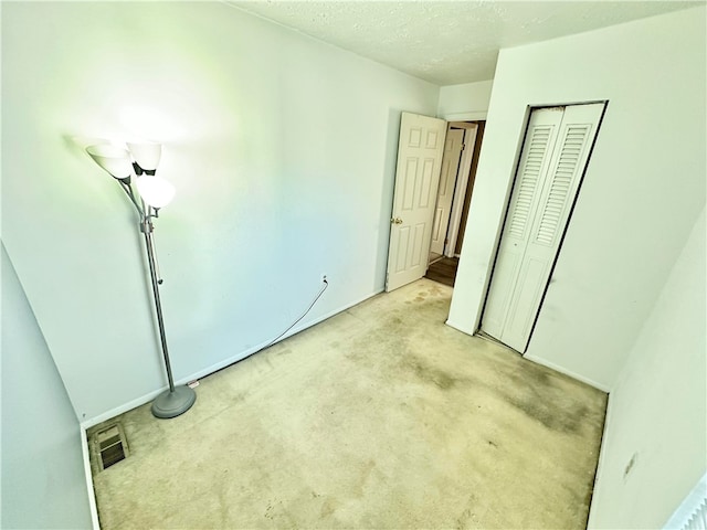 unfurnished bedroom featuring light carpet, a closet, and a textured ceiling