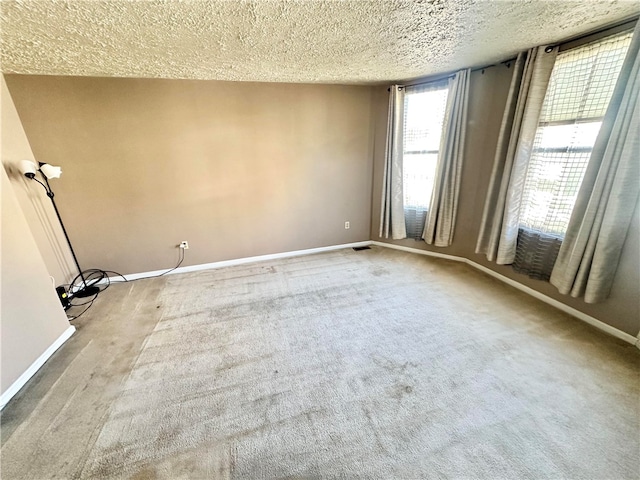 carpeted spare room featuring a textured ceiling and plenty of natural light