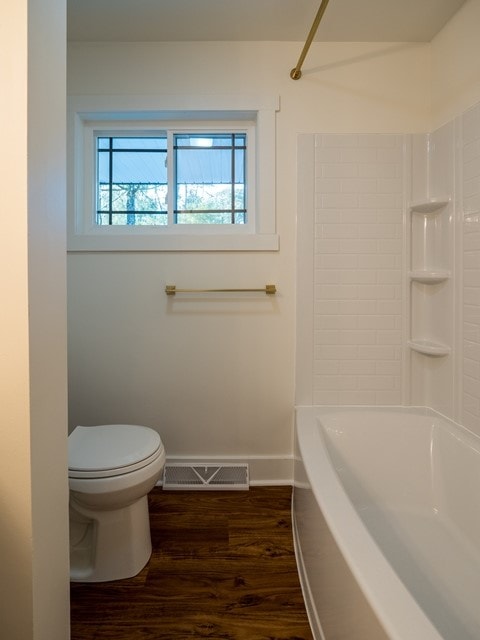 bathroom featuring toilet, hardwood / wood-style flooring, and  shower combination