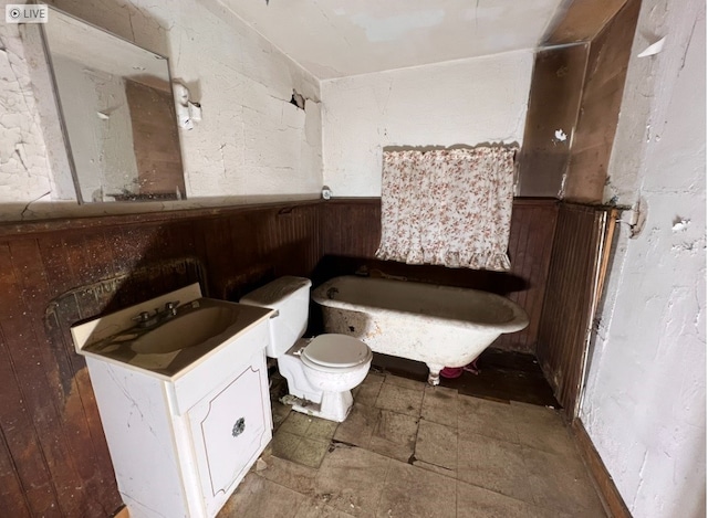 bathroom featuring toilet, wood walls, and vanity