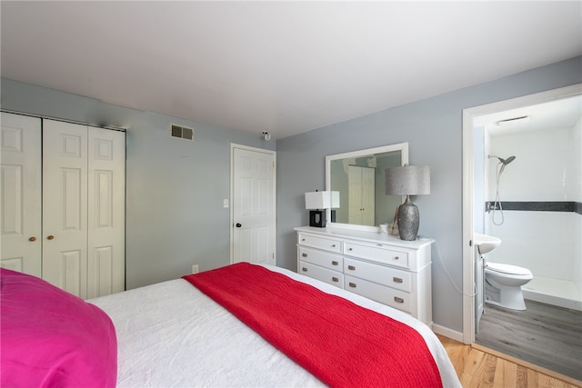 bedroom with connected bathroom, light hardwood / wood-style floors, and a closet