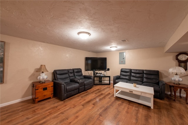 living room featuring a textured ceiling, hardwood / wood-style flooring, and electric panel