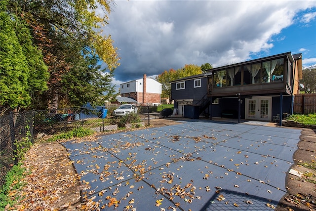 back of property featuring french doors, a patio, and a covered pool