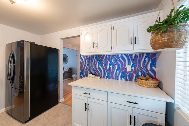 kitchen featuring stainless steel fridge, white cabinets, and light wood-type flooring