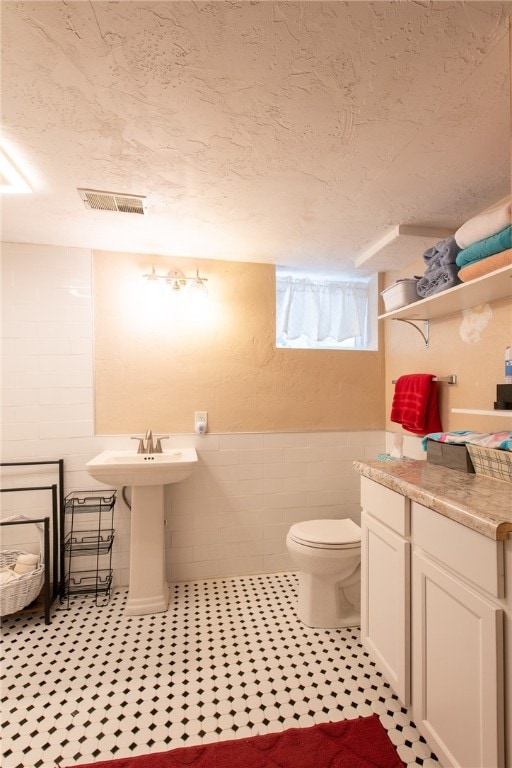 bathroom featuring toilet, sink, and tile walls