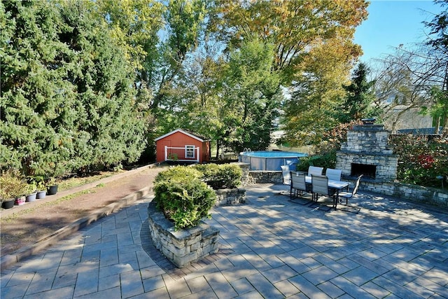 view of patio with an outdoor stone fireplace and a shed