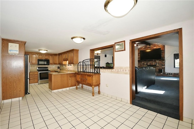 kitchen featuring stainless steel appliances, a brick fireplace, tasteful backsplash, brick wall, and kitchen peninsula