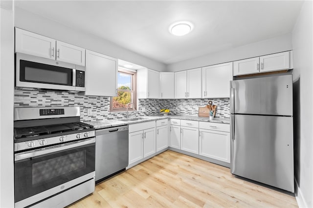 kitchen with white cabinets, stainless steel appliances, sink, and light wood-type flooring