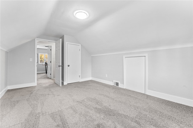 bonus room featuring vaulted ceiling and light colored carpet