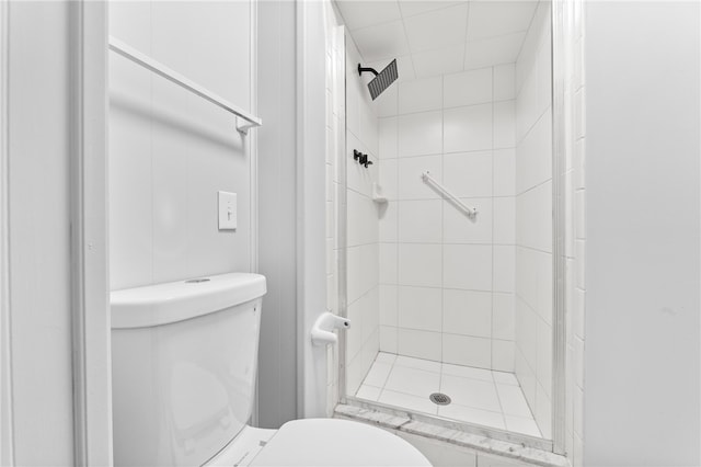 bathroom with a tile shower and toilet