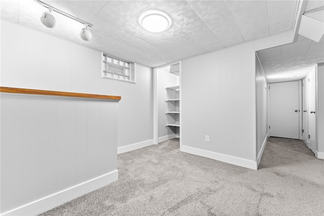 basement featuring track lighting and light carpet