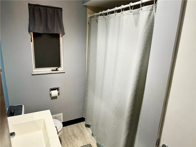 bathroom featuring toilet, sink, hardwood / wood-style flooring, and curtained shower