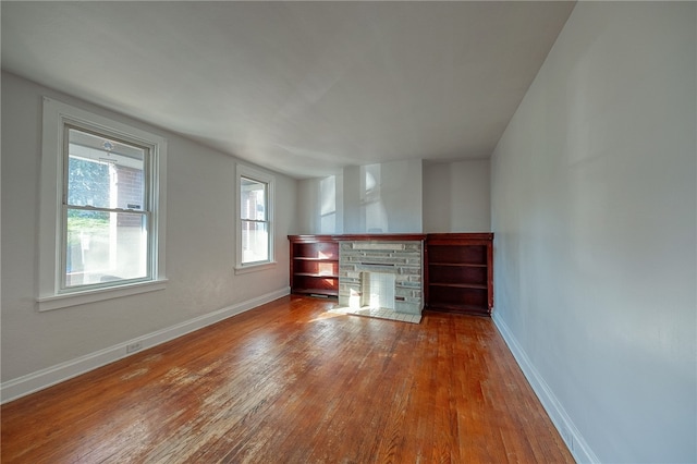 unfurnished living room featuring a stone fireplace and hardwood / wood-style flooring