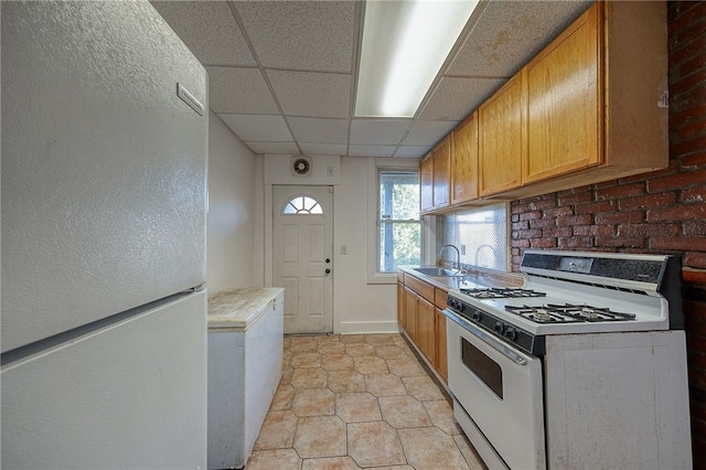 kitchen featuring white appliances, a paneled ceiling, light tile patterned flooring, and sink