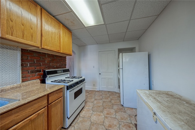 kitchen with white appliances, light tile patterned floors, and a drop ceiling