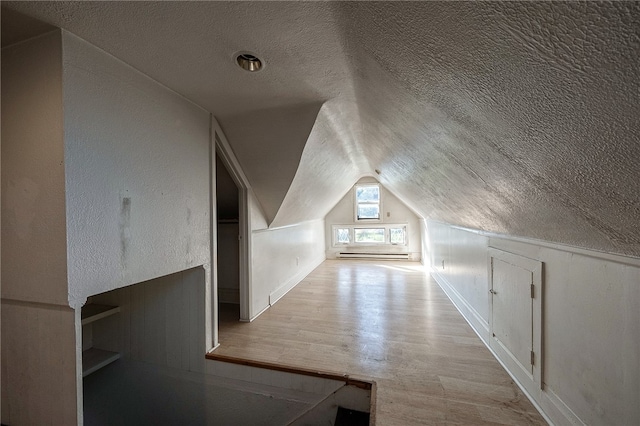 bonus room featuring light hardwood / wood-style floors, a textured ceiling, and lofted ceiling