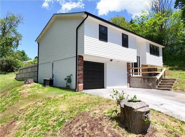 exterior space featuring a garage, a front yard, and central AC