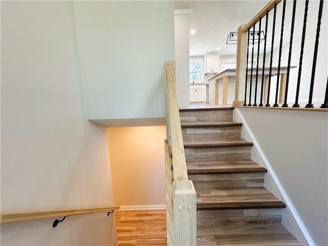 staircase with hardwood / wood-style floors and sink