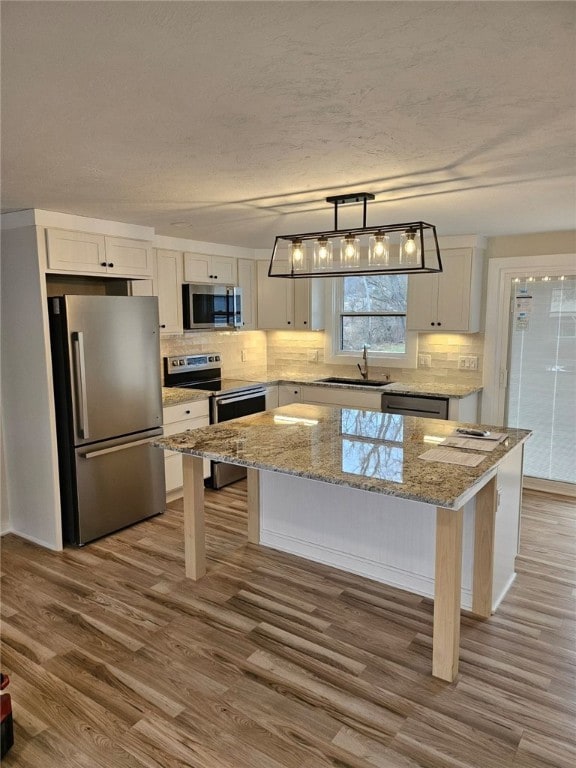 kitchen with a kitchen island, dark hardwood / wood-style flooring, pendant lighting, white cabinets, and appliances with stainless steel finishes