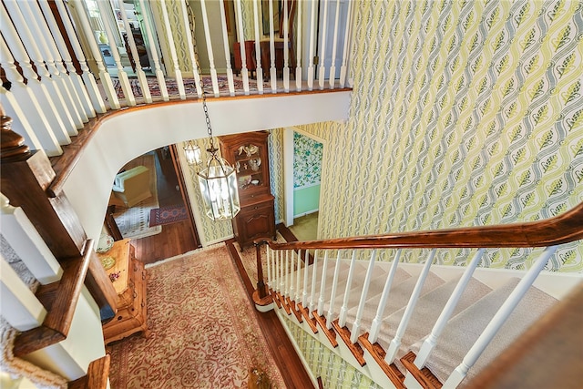 stairs with hardwood / wood-style flooring and a chandelier