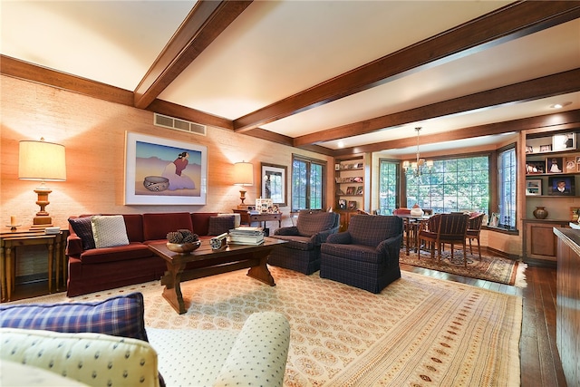 living room featuring beam ceiling, hardwood / wood-style flooring, and an inviting chandelier