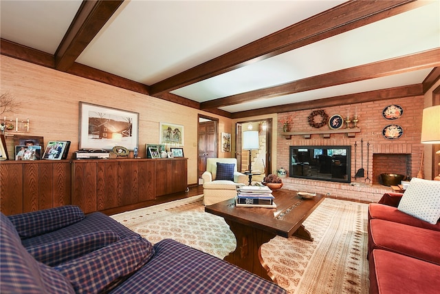 living room featuring beam ceiling, a brick fireplace, and hardwood / wood-style floors