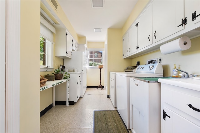 laundry room with a healthy amount of sunlight, cabinets, and washing machine and clothes dryer