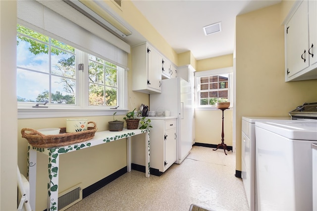 kitchen with a wealth of natural light, white cabinets, and washing machine and dryer