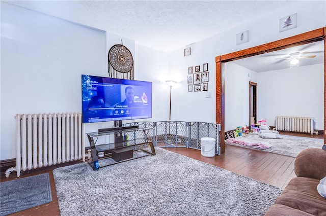 living room featuring a textured ceiling, ceiling fan, radiator heating unit, and hardwood / wood-style flooring