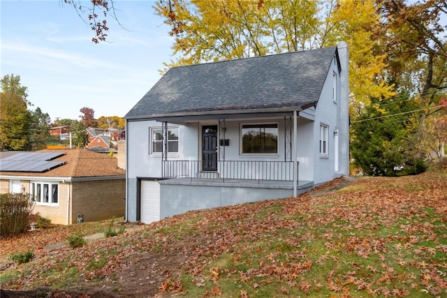 bungalow with solar panels, a porch, and a garage