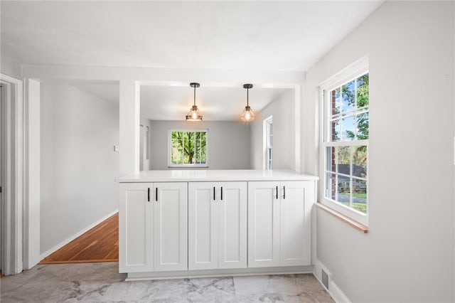 kitchen featuring white cabinetry, a healthy amount of sunlight, light hardwood / wood-style flooring, and pendant lighting